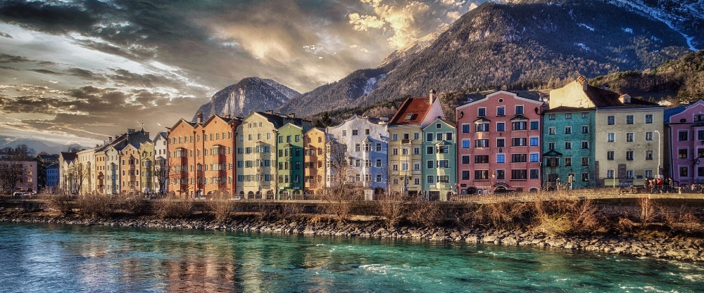 Casas de colores alineadas junto al río Inn con los picos nevados de los Alpes de fondo en Innsbruck.